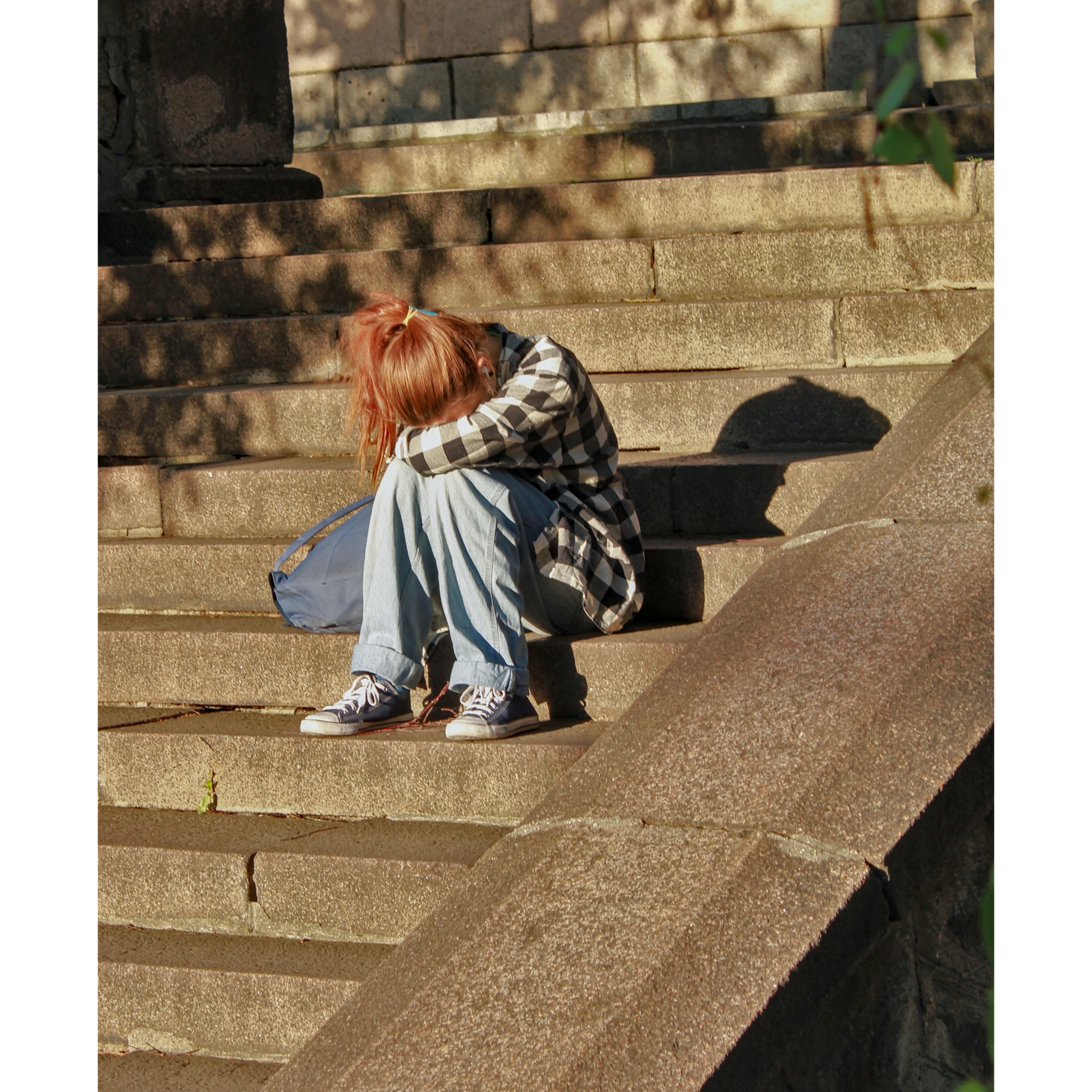 Teenager sitting on steps with her head in her hands.